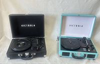 Black and teal Victrola record players open, showing platters, tonearms and interiors