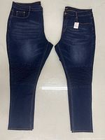 Both pairs of navy jeans side by side showing size difference, tags, and design details
