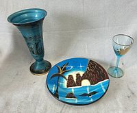 Vase, decorative plate and wine glass arranged together