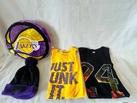 All four Lakers fan items: plush pillow, beanie, yellow tank, black 24 tank