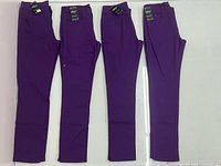 Four pairs of purple QQMY pants laid flat showing tags and condition