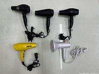 Top-down view of all five blow dryers laid out showing colours and cords
