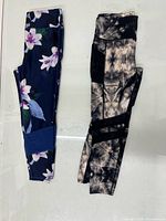 Navy floral print leggings and black-grey tie-dye leggings laid side by side