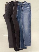 Five pairs of jeans laid flat showing full length