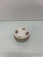 Stack of six floral saucers showing gold rims