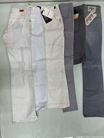 Five pairs of jeans laid out front view displaying colors and tags