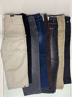 All eight pairs of men’s jeans laid flat side by side showing front view and color variety