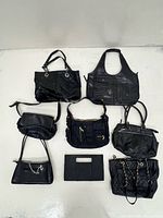Overview of eight assorted black handbags laid out