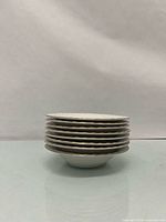 Stack of eight white scalloped-edge saucers