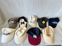 Nine assorted baseball caps laid out showing logos and colours