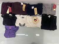 Nine folded long-sleeve tops displaying colours and tags