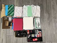 All office supply items laid out including paper reams, tape boxes, folders, laminating pouches, binder clips, staples and organizer tray