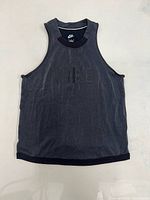 Front view of dark grey Nike women’s medium tank top showing tonal logo and design details