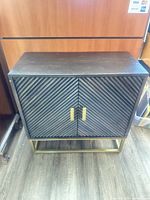 Front view of black chevron cabinet with gold hardware and base