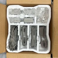Top view of opened box showing coiled grey cables and bagged components in styrofoam insert