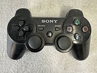 Front view of black Sony DualShock 3 controller showing buttons and sticks
