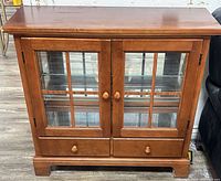 Front view of brown wood cabinet with glass doors and drawers