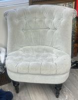 Front view showing tufted back, seat, rolled arms, turned legs
