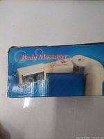 Retail box top showing product name Body Massager and partial image of handheld device