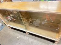 Front angled view of cabinet showing sliding glass doors, interior glass shelves, and wood veneer finish