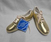 Top view of pair of metallic gold shoes with hang tag