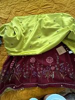 Chartreuse satin throw over burgundy floral embroidered throw showing embroidery and fabric texture