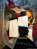 Assorted items in metal sleigh tray including Marquis Waterford box, red finial topper, ribbons, pillow edge visible