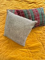 Silver beaded square pillow and plaid lumbar pillow on yellow surface