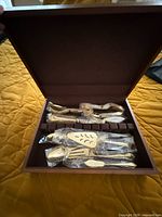 Open storage chest showing sleeved gold flatware