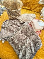 Group view of faux fur shrug, woven throw, plush throw in packaging