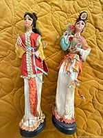 Front view of both figurines standing on bedspread
