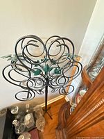 ornate wrought iron stand with scrolls and green leaf accents