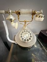 Front view of glass and brass-tone corded telephone on desk
