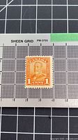 Front view of orange 1¢ Canada king portrait stamp on grid for scale