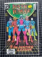 Front cover of bagged Justice League International #23 on grid background