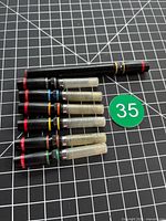 Pen body and six nib assemblies laid out on grid cutting mat