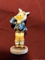 Front view of Hummel boy with toothache figurine on cream base
