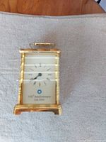 Front view of gold-tone carriage clock displaying dial and anniversary inscription