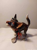 Front angled view of multicolored cat figurine showing facial details and attached dish