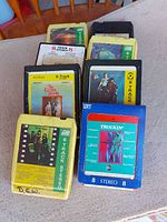 Row of nine 8-track tapes on tabletop, full lot visible
