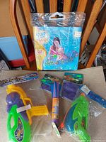 Overall lot showing baby float package, water pistols, foam rocket, swim cap packages