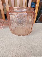 Side view of pink depression glass biscuit jar showing paneled body and floral motif