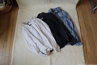 All three shirts laid flat: white patterned, navy, denim