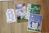 Four religious songbooks laid out on wooden floor showing covers