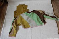 Mustard sleeveless top under multicolor knit sweater on backdrop