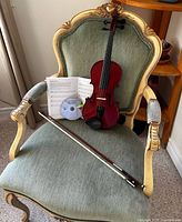 Front view of violin on chair with bow, open song book and DVD visible