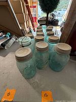 All ten Ball aqua mason jars lined on table showing lids