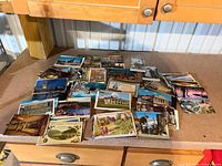 Wide view of entire stack of assorted postcards on workbench