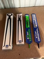 Boxed Mustad tongs and eXcel rasps side by side