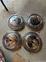 All four hubcaps, chrome finish, concentric ring design, bowtie emblems visible